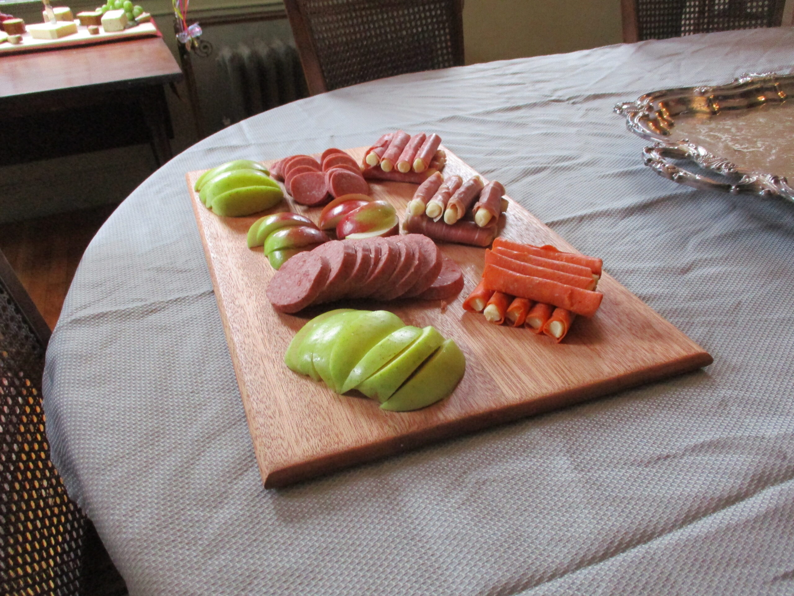 Custom all Mahogany cutting board/charcuterie board as a housewarming gift pictured with fruit and cured meats.