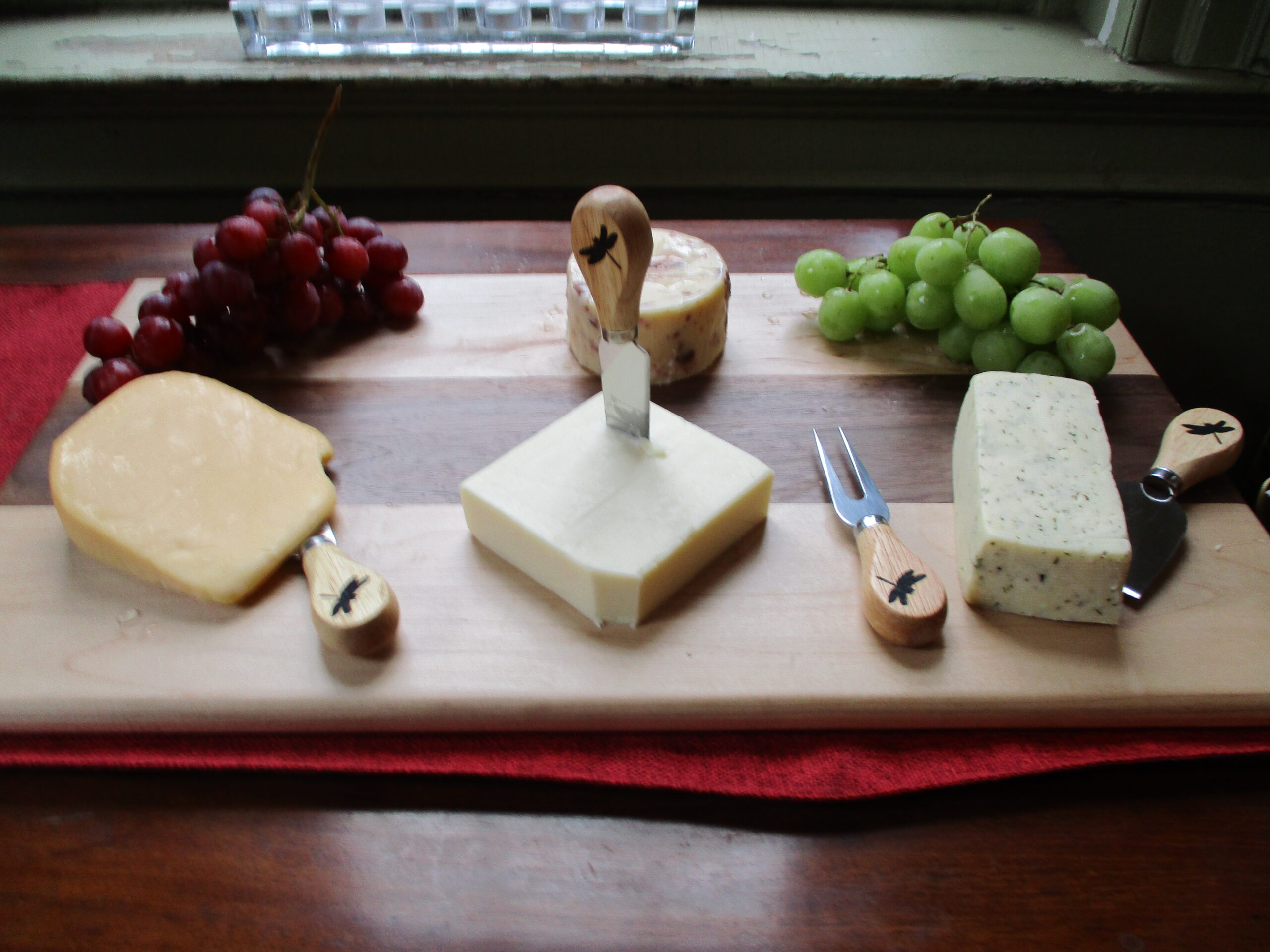 Custom Maple and Walnut cutting board/charcuterie board as a housewarming gift pictured with fruit and cheese.