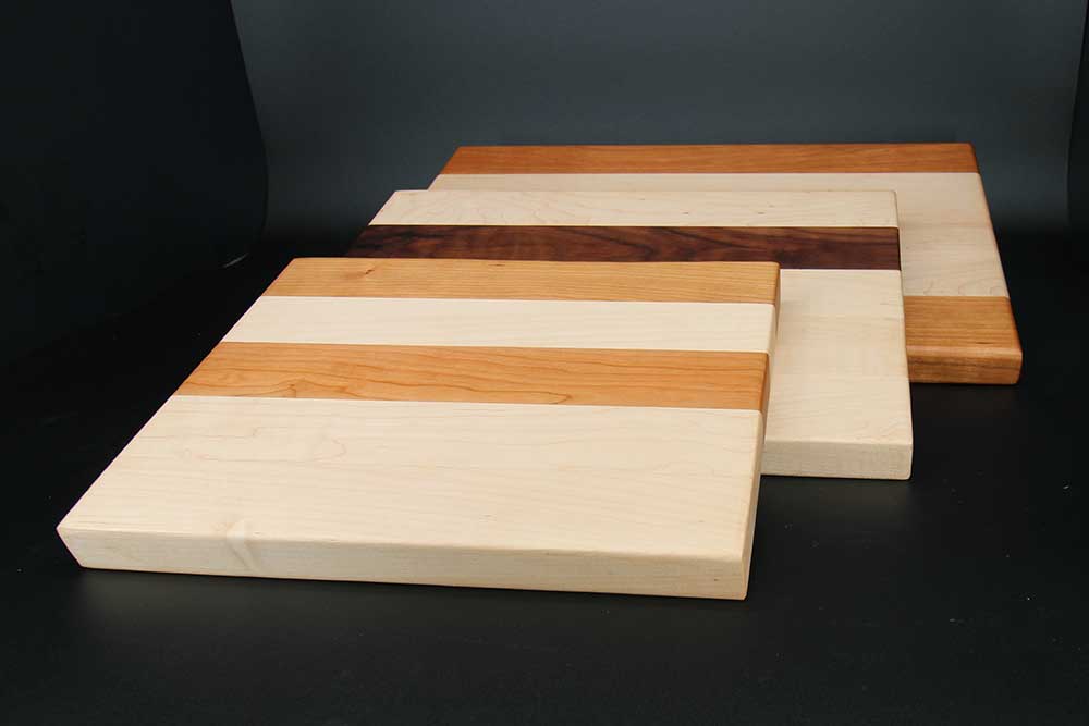 Three cutting boards made of maple wood with accents of walnut wood and cherry wood