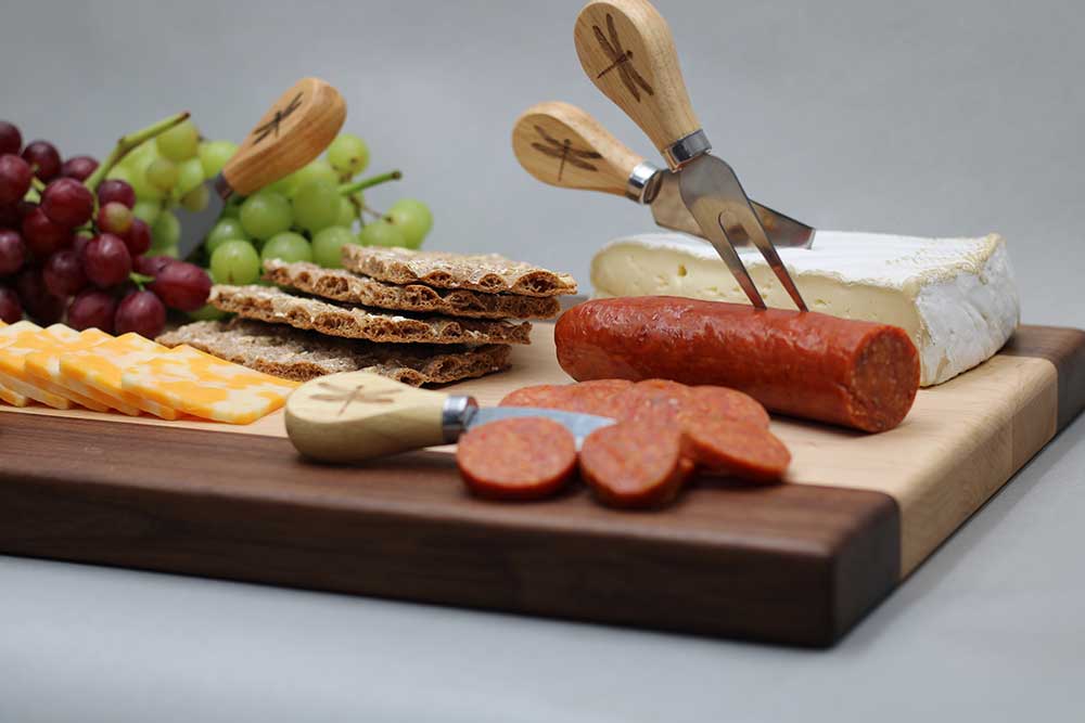 Walnut and maple charcuterie board with cutlery smoked sausage brie grapes colby jack and crackers charcuterie gift