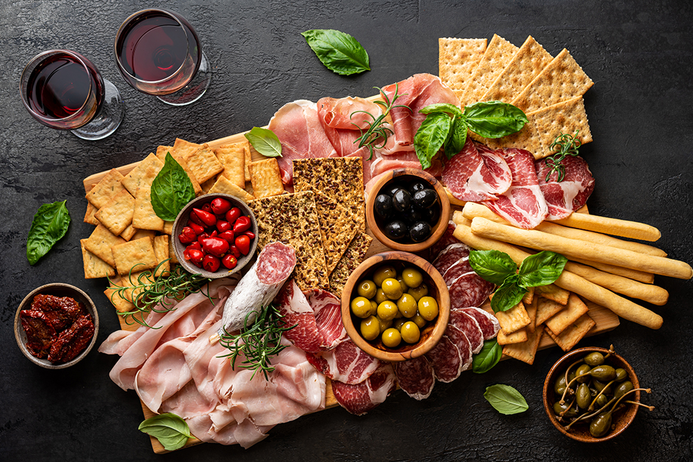 Appetizers with differents antipasti, charcuterie, snacks and red wine. Sausage, ham, tapas, olives and crackers for buffet party. Top view, flat lay