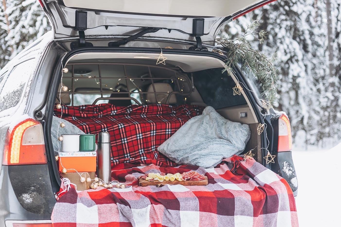 A car trunk decorated for a celebration winter picnic with a wood charcuterie board.